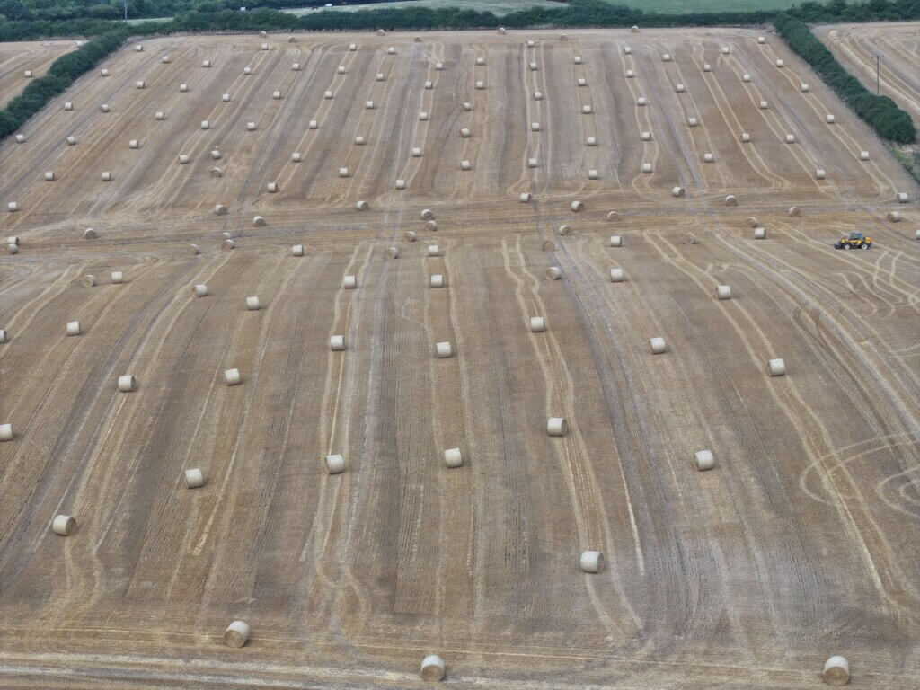 agricultural building on land with bales of hay